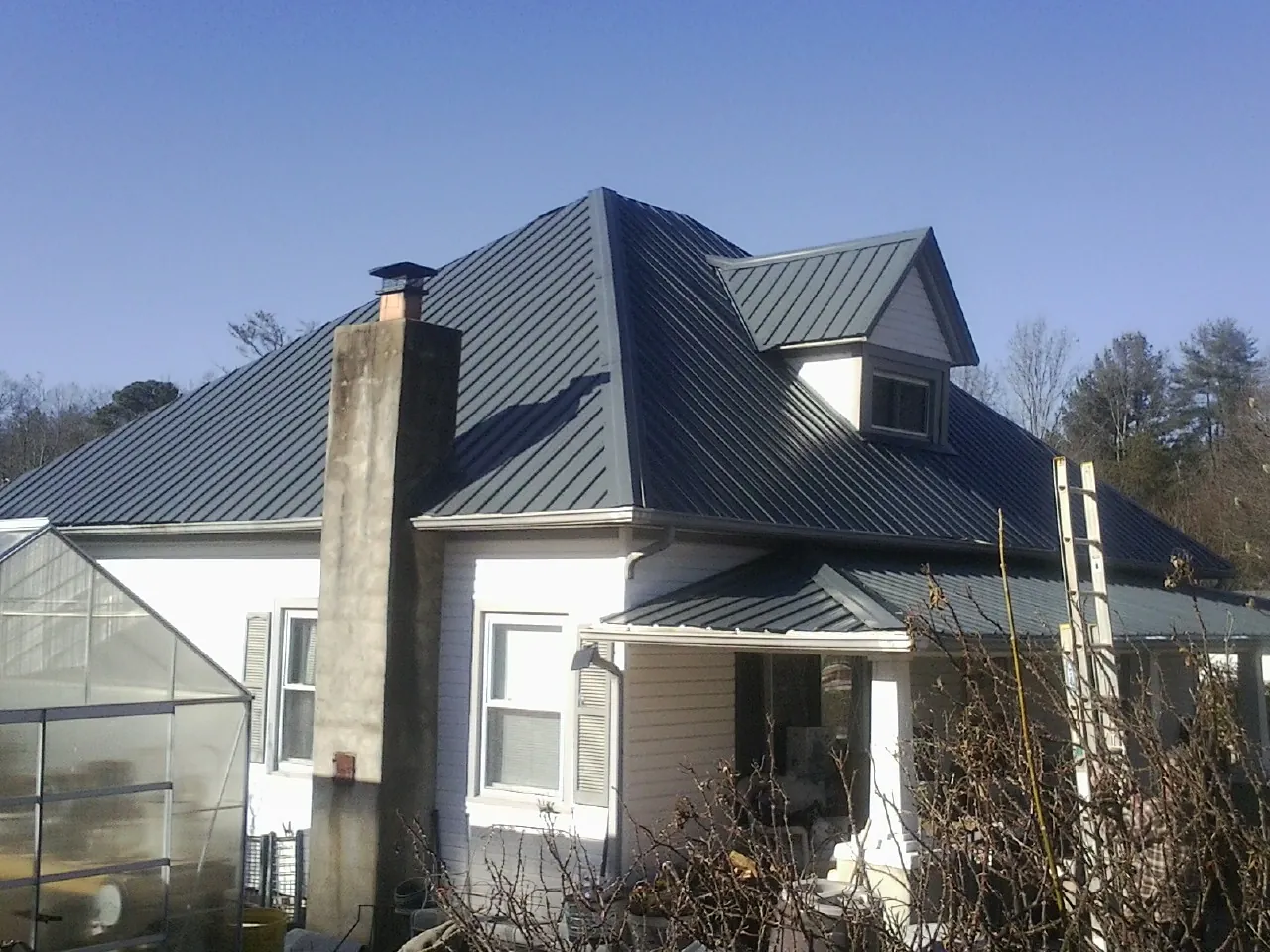 Dark blue standing seam metal roof on a white farmhouse with dormer — Slate & Tile Roof Repair by Roofing Brothers in Wells Tannery