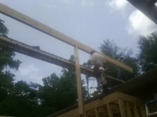 Carpenter setting a ridge beam over a new addition frame — Ice Dam Removal by Roofing Brothers in Wells Tannery