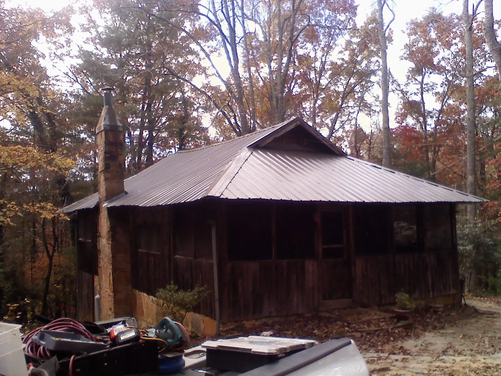 Brown metal hip roof on an old cabin with a stone chimney in Wells Tannery