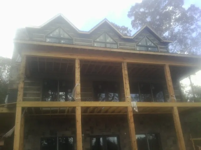 Dormers and porch framing on a large log home under construction — Roof Coating work by our crew in Wells Tannery