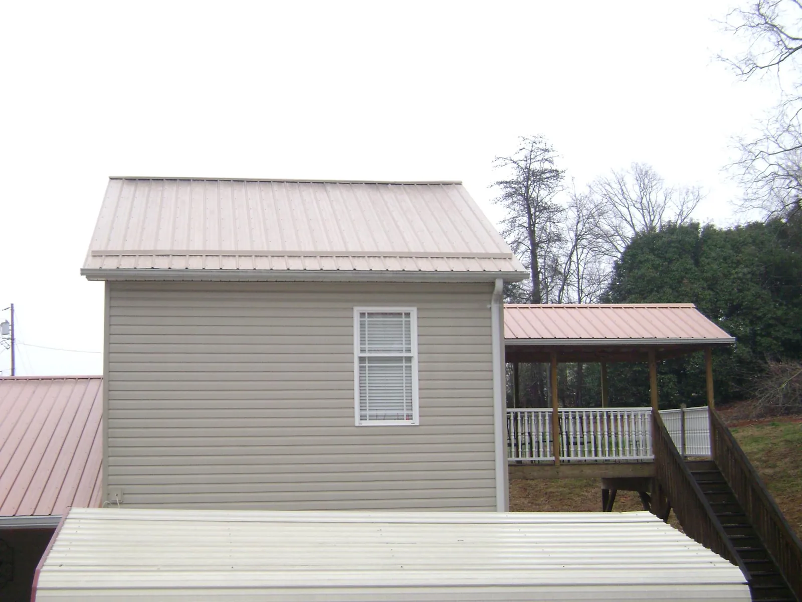 Tan metal roofs on a two story addition and attached porch, from a Roof Replacement job in Wells Tannery