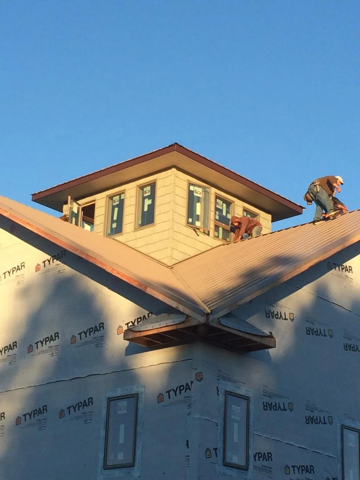 Roofers working around a rooftop cupola on a new metal roof at sunset — Roof Waterproofing in Wells Tannery by Roofing Brothers